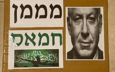 La pancarte brandie par Guri Lotan portant l'inscription « Financeur du Hamas » au-dessus d'une photo du Premier ministre Benjamin Netanyahu et d'un drapeau du groupe terroriste palestinien du Hamas, lors de la manifestation à Haïfa, le 4 août 2026. (Crédit : Capture d'écran/X) La pancarte brandie par Guri Lotan portant l'inscription « Financeur du Hamas » au-dessus d'une photo du Premier ministre Benjamin Netanyahu et d'un drapeau du groupe terroriste palestinien du Hamas, lors de la manifestation à Haïfa, le 4 août 2026. (Crédit : Capture d'écran/X)