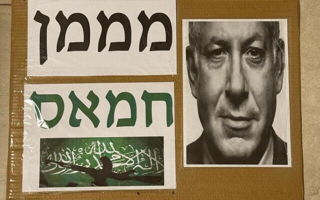 La pancarte brandie par Guri Lotan portant l'inscription « Financeur du Hamas » au-dessus d'une photo du Premier ministre Benjamin Netanyahu et d'un drapeau du groupe terroriste palestinien du Hamas, lors de la manifestation à Haïfa, le 4 août 2026. (Crédit : Capture d'écran/X) La pancarte brandie par Guri Lotan portant l'inscription « Financeur du Hamas » au-dessus d'une photo du Premier ministre Benjamin Netanyahu et d'un drapeau du groupe terroriste palestinien du Hamas, lors de la manifestation à Haïfa, le 4 août 2026. (Crédit : Capture d'écran/X)