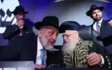 Le chef de Shas, Aryeh Deri, avec le rabbin Yitzhak Yosef, leader spirituel de Shas, sur scène lors du lancement officiel de la campagne électorale du parti, à Holon, dans le centre d'Israël, le 21 août 2026. (Crédit : Yaakov Cohen)