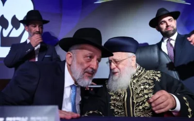 Le chef de Shas, Aryeh Deri, avec le rabbin Yitzhak Yosef, leader spirituel de Shas, sur scène lors du lancement officiel de la campagne électorale du parti, à Holon, dans le centre d'Israël, le 21 août 2026. (Crédit : Yaakov Cohen)