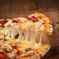 Une part de pizza. La bêta-caséine, dont l'introduction dans une plante a été réalisée avec succès à l'Université hébraïque de Jérusalem, est l'une des protéines du lait qui permettent au fromage de fondre. (Crédit : Proformabooks, iStock by Getty Images)