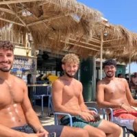 Nitzan Eliyahu, Shon Brener et Omer Maoz bronzent sur la plage de Shavei Zion, en Galilée occidentale, le 16 juillet 2026. (Diana Bletter/Times of Israel)
