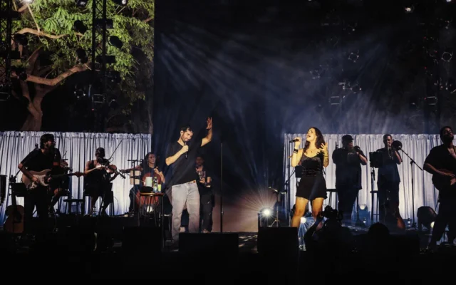 L'ancien otage Sagui Dekel-Chen et la chanteuse Marina Maximilian interprétant les chansons qu'il a composées pendant sa captivité, sur la pelouse du kibboutz Nir Oz, dans le cadre du Festival d'Israël, le 10 août 2026. (Crédit : Orit Pnini)