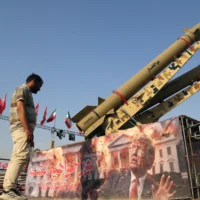 Un homme observe une banderole à l'effigie du président américain Donald Trump, déployée devant les missiles balistiques "Zolfaghar" et "Zolghadr" exposés sur la place Azadi à Téhéran, la capitale iranienne, le 2 août 2026. (Fatemeh Bahrami / Anadolu via Reuters)