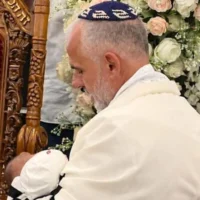 Yigal Sarusi, père endeuillé de l'otage assassiné Almog Sarusi, tenant son fils nouveau-né dans ses bras, le 28 septembre 2026. (Crédit : Autorisation)