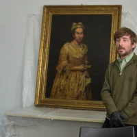 Ariel Bassano, professeur d'arts plastiques, s'exprimant devant un tableau intitulé "Portrait d'une dame", volé par les nazis à un collectionneur d'art juif néerlandais, exposé au parquet de Mar del Plata, en Argentine, le 3 septembre 2025. (Crédit: AFP)