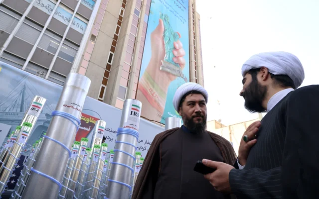Des hommes se tenant à côté d’une maquette de missile et d’une centrifugeuse d’enrichissement nucléaire lors d’un rassemblement devant l’ancienne ambassade américaine à Téhéran, alors que les Iraniens commémorent le 46e anniversaire du début de la crise des otages en Iran, le 4 novembre 2025. (Crédit: Atta Kenare/AFP)