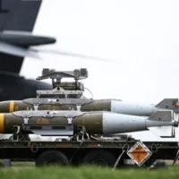Du personnel au sol de l'armée de l'air américaine préparant des munitions d'attaque directe interarmées (JDAM) destinées à un bombardier B-1 Lancer sur le tarmac de la base RAF Fairford, dans le sud-ouest de l'Angleterre, le 12 mars 2026. (Crédit : Henry Nicholls/AFP)