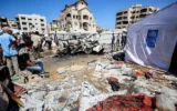 Des personnes se rassemblent près d’un véhicule détruit par une frappe israélienne dans le quartier de Rimal, à Gaza-City, le 1ᵉʳ septembre 2026. (Crédit : Omar AL-QATTAA/AFP)