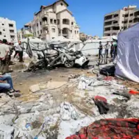 Des personnes se rassemblent près d’un véhicule détruit par une frappe israélienne dans le quartier de Rimal, à Gaza-City, le 1ᵉʳ septembre 2026. (Crédit : Omar AL-QATTAA/AFP)