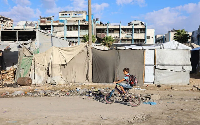 Illustration : Un enfant gazaoui passant à vélo devant des abris de fortune en se rendant à l’école, à l’occasion de la rentrée scolaire à Gaza-City, au nord de la bande de Gaza, le 19 septembre 2026. (Crédit : Omar al-Qattaa/AFP)