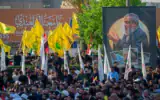 Des personnes rassemblées près d'un portrait géant de l'ancien chef du groupe terroriste chiite libanais du Hezbollah, Hassan Nasrallah, sur la place Tahrir, à Bagdad, le 26 septembre 2026, pour marquer le deuxième anniversaire de son élimination lors d'une frappe israélienne de grande envergure contre la banlieue sud de Beyrouth, au Liban. (Crédit : Murtadha Ridha/AFP)