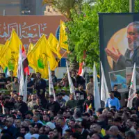 Des personnes rassemblées près d'un portrait géant de l'ancien chef du groupe terroriste chiite libanais du Hezbollah, Hassan Nasrallah, sur la place Tahrir, à Bagdad, le 26 septembre 2026, pour marquer le deuxième anniversaire de son élimination lors d'une frappe israélienne de grande envergure contre la banlieue sud de Beyrouth, au Liban. (Crédit : Murtadha Ridha/AFP)
