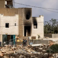 Des extrémistes juifs et les forces de sécurité près d’une maison endommagée par un incendie à Jalud, au sud de Naplouse, en Cisjordanie, le 29 septembre 2026. (Crédit: Zain JAAFAR/AFP)