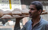 Un homme portant un plateau de pain sur un marché populaire du Caire, en Égypte, le 7 juin 2024. (Crédit :  Amr Nabil/AP)