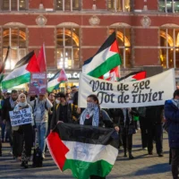 Illustration : Des manifestants anti-Israël tenant une pancarte sur laquelle est écrit "Chaque jour est le 7-Octobre », tandis qu’une banderole porte l’inscription "De la mer jusqu'au fleuve", lors d’une manifestation organisée en même temps qu’une commémoration pro-Israël marquant l’anniversaire du pogrom du Hamas du 7 octobre 2023, à Amsterdam, aux Pays-Bas, le 7 octobre 2024. (Crédit : Peter Dejong/AP Photo)
