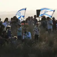 Des militants de droite participent à un rassemblement appelant au rétablissement des implantations juives dans la bande de Gaza, près de la frontière, dans le sud d'Israël, le 30 juillet 2025. (AP Photo/Ohad Zwigenberg)