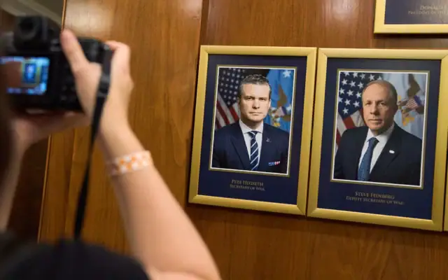 Un photographe prend une photo des portraits des dirigeants du département au Pentagone, après que le président américain Donald Trump a signé un décret visant à renommer le ministère de la Défense en "ministère de la Guerre" à Washington, le 9 septembre 2025. À gauche, le secrétaire à la Défense Pete Hegseth et, à droite, son adjoint Steve Feinberg. (Crédit: AP/Jacquelyn Martin)