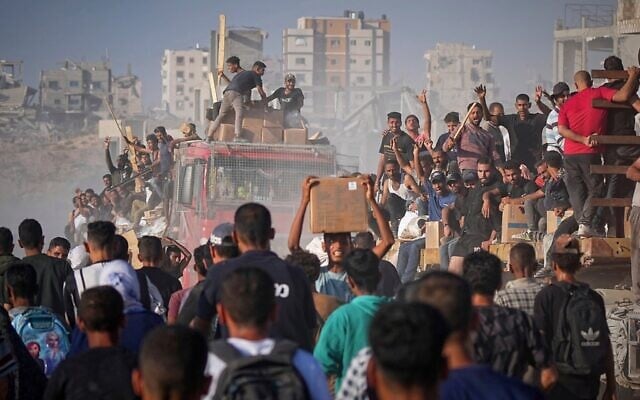 Des Gazaouis montant à bord d'un camion chargé de denrées alimentaires et d'aide humanitaire provenant du Programme alimentaire mondial, après son arrivée dans le nord de la bande de Gaza, le 16 juin 2025. (Crédit : Jehad Alshrafi/AP)