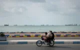 Deux hommes circulent à moto le long du littoral alors que des navires commerciaux sont ancrés dans le détroit d'Ormuz, au large de Bandar Abbas, en Iran, le 4 septembre 2026. (AP Photo/Vahid Salemi)