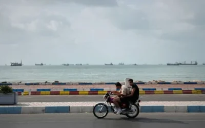 Deux hommes circulent à moto le long du littoral alors que des navires commerciaux sont ancrés dans le détroit d'Ormuz, au large de Bandar Abbas, en Iran, le 4 septembre 2026. (AP Photo/Vahid Salemi)
