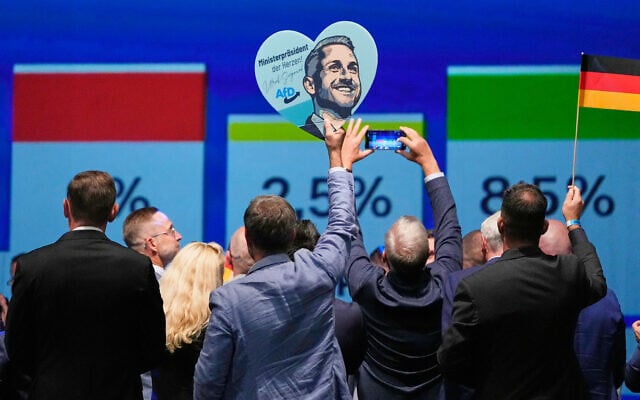 Des membres du parti célèbrent leur victoire avec une pancarte à l'effigie d'Ulrich Siegmund, tête de liste de l'AfD, après les premiers résultats des élections régionales de Saxe-Anhalt à Magdebourg, dans l'est de l'Allemagne, le dimanche 6 septembre 2026. (Crédit : AP/Matthias Schrader)