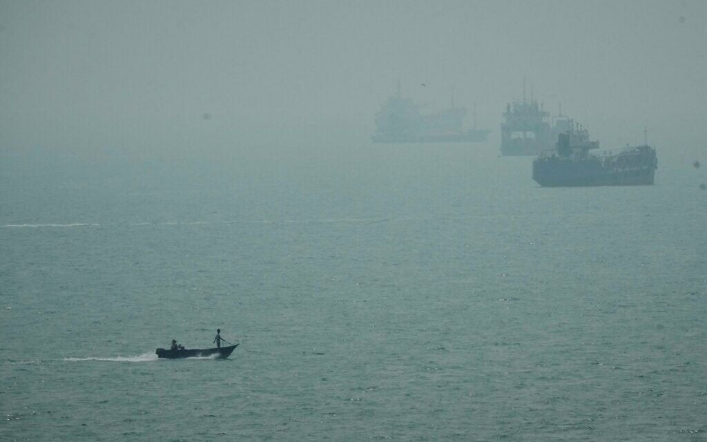Un bateau à moteur passant devant des navires commerciaux ancrés dans la brume dans le détroit d'Ormuz, au large de Bandar Abbas, en Iran, le 7 septembre 2026. (Crédit : Vahid Salemi/AP)