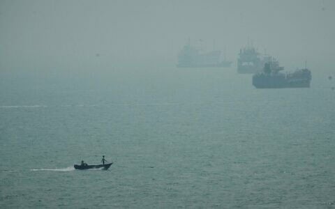 Un bateau à moteur passant devant des navires commerciaux ancrés dans la brume dans le détroit d'Ormuz, au large de Bandar Abbas, en Iran, le 7 septembre 2026. (Crédit : Vahid Salemi/AP)