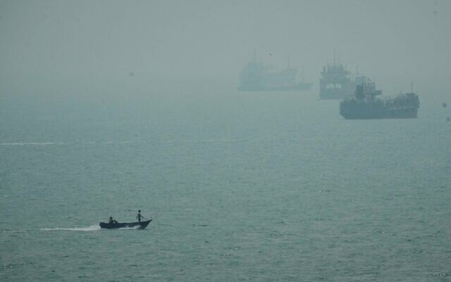 Un bateau à moteur passe dans la brume devant des navires marchands ancrés dans le détroit d'Ormuz, au large de Bandar Abbas, en Iran, le 7 septembre 2026. (Crédit : AP Photo/Vahid Salemi)