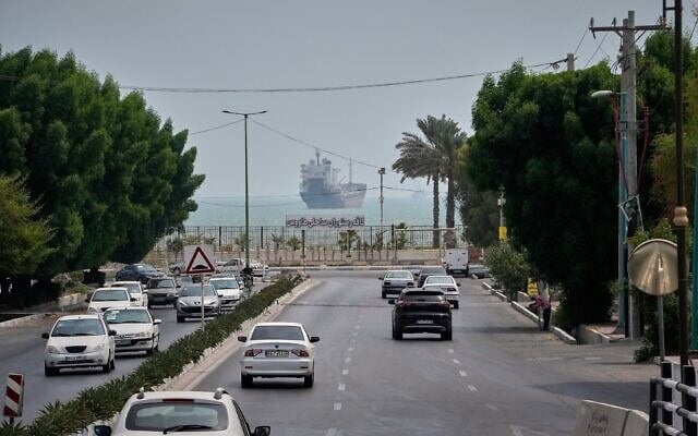 Des voitures circulent sur une avenue tandis qu'un navire marchand est à l'ancre dans le détroit d'Ormuz, au large de Bandar Abbas, en Iran, le 7 septembre 2026. (Crédit : AP Photo/Vahid Salemi)