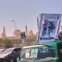 Un homme se tient près d’un portrait du chef terroriste houthi Mohammed Omar Ali al-Saqqaf, également connu sous le nom d’Abu Fatima, accroché à une camionnette lors d’un important cortège funèbre, avec la mosquée Al-Saleh en arrière-plan, à Sanaa, au Yémen, le 16 septembre 2026. (Crédit : AP)