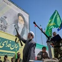 Un religieux chiite armé passe à bord d'un véhicule militaire devant un panneau d'affichage représentant l'ayatollah Ruhollah Khomeini, fondateur de la République islamique, lors du défilé militaire dit « Janfada », ou « Sacrifice pour l'Iran », organisé par l'État à Téhéran, en Iran, le 18 septembre 2026. (Crédit : AP Photo/Vahid Salemi)