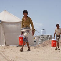 Des Yéménites déplacés transportant de l'eau dans le camp d'Al-Firdaws, à Ras Imran, dans la banlieue ouest d'Aden, au Yémen, le 21 septembre 2026. (Crédit : Abdulnasser Alseddik/AP Photo)