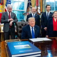 Le président américain Donald Trump fait un clin d'œil aux journalistes depuis le bureau ovale de la Maison-Blanche, entouré de membres de son administration et d'élus, le 28 septembre 2026 à Washington. (AP Photo/Alex Brandon)