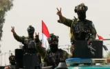 Des agents de sécurité irakiens faisant le signe de la victoire depuis des véhicules décorés de drapeaux nationaux, au sein d'un convoi célébrant le retrait total des troupes américaines d'Irak, à Bagdad, en Irak, le 30 septembre 2026. (Crédit : Hadi Mizban/AP)