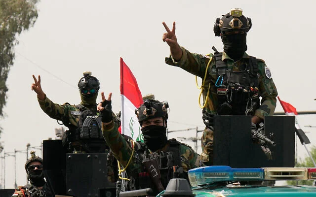 Des agents de sécurité irakiens faisant le signe de la victoire depuis des véhicules décorés de drapeaux nationaux, au sein d'un convoi célébrant le retrait total des troupes américaines d'Irak, à Bagdad, en Irak, le 30 septembre 2026. (Crédit : Hadi Mizban/AP)