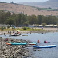 Des personnes profitent du lac de Tibériade, dans le nord d'Israël lors d'une chaude journée d'été, le 2 août 2026. (Crédit : Michael Giladi/Flash90)