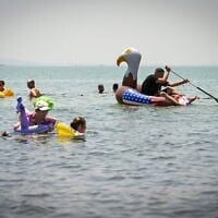 Des gens profitant du lac de Tibériade, dans le nord d'Israël, lors d'une chaude journée d'été, le 2 août 2026. (Crédit : Michael Giladi/Flash90)