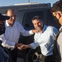 Le député Simcha Rothman (à gauche) et le ministre des Finances, Bezalel Smotrich (à droite), encadrés par des agents de sécurité masqués, arrivant à une cérémonie marquant la création de la nouvelle implantation israélienne de Maale Arugot, dans le Gush Etzion, en Cisjordanie, le 2 septembre 2026. (Crédit : Chaïm Goldberg/Flash90)
