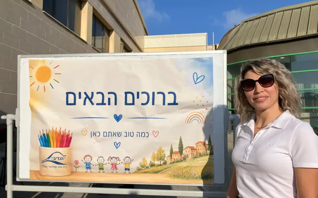 Noleen Safadi, responsable du département de l'éducation de Metula et habitante de Majdal Shams, devant un panneau indiquant « Bienvenue » devant l'école primaire Hanadiv de Metula, le 1ᵉʳ septembre 2026. (Crédit : Diana Bletter/Times of Israel)