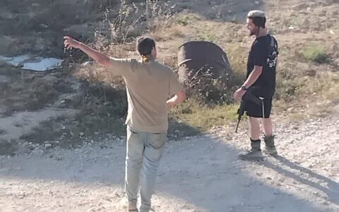 Des résidents d'implantation dans la cour d’une maison palestinienne avant de s’en emparer, dans le village de Jalud, en juillet 2026. (Crédit : Autorisation)