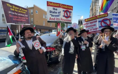 Yehonatan Ovadia, à gauche, brandit un drapeau palestinien alors qu’il participe à une manifestation anti-Israël aux côtés d’autres juifs hassidiques antisionistes tenant des pancartes du groupe Neturei Karta, sur une photo non datée. (Crédit : Eric Lee/JTA)