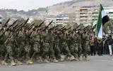 Des personnes agitant des drapeaux syriens alors qu’elles assistent à un défilé militaire célébrant le premier anniversaire de la chute de Bachar al-Assad, dictateur de longue date, à Damas, le 8 décembre 2025. (Crédit : Louai Beshara/AFP)