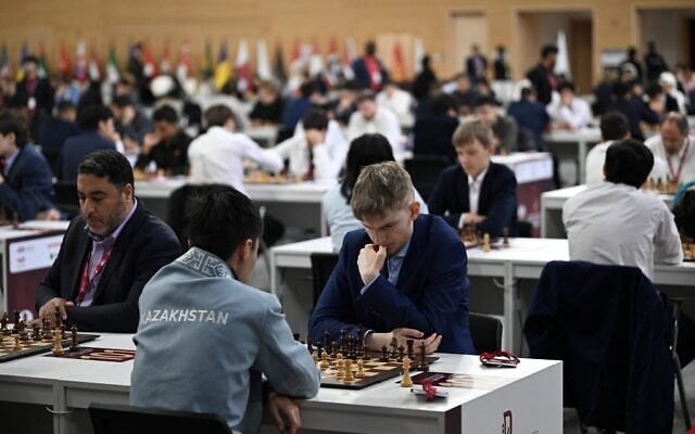 Des concurrents sont assis à leurs tables lors de la première manche des Championnats du monde de rapid et de blitz de la FIDE 2025, au Complexe des sports et des événements de l'Université du Qatar, à Doha, au Qatar, le 27 décembre 2025. (Crédit : Mahmud HAMS/AFP)