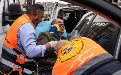 Jaafar Ashtiyeh, photographe de l'Agence France-Presse (AFP), est transporté par des secouristes palestiniens pour recevoir des soins médicaux après avoir été passé à tabac par plusieurs Israéliens à Aqraba, en Cisjordanie, le 6 octobre 2026. (Crédit : JOHN WESSELS/AFP)
