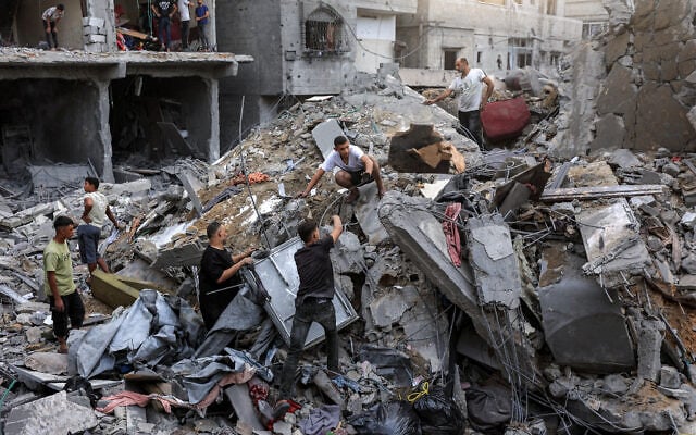 Des personnes fouillent les décombres d’un bâtiment effondré à la suite des frappes aériennes israéliennes menées dans la nuit du 9 octobre 2026 à Gaza-City, avant lesquelles l’armée israélienne avait averti les habitants de quitter la zone. (Crédit : Omar AL-QATTAA/AFP)