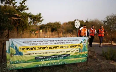 Le personnel soignant passant devant une banderole indiquant que l'accès est interdit aux randonneurs, près du lieu où une munition non explosée du groupe terroriste chiite libanais du Hezbollah a explosé lors d'une randonnée scolaire dans la périphérie de Yiftah, près de la frontière libanaise, dans le nord d'Israël, le 12 octobre 2026. (Crédit : Jalaa Marey/AFP)
