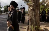 Des Juifs ultra-orthodoxes attendant à un arrêt de bus à Arad, le 1ᵉʳ octobre 2026. (Crédit : John Wessels/AFP)