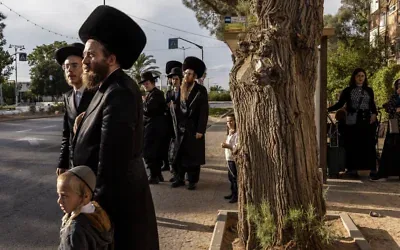 Des Juifs ultra-orthodoxes attendant à un arrêt de bus à Arad, le 1ᵉʳ octobre 2026. (Crédit : John Wessels/AFP)