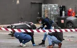 Des policiers examinent des preuves dans une station-service où un homme a ouvert le feu depuis son véhicule, faisant un mort et quatre blessés de source policière, à Trappes, en banlieue parisienne, le 23 octobre 2026. (Dimitar DILKOFF/AFP)